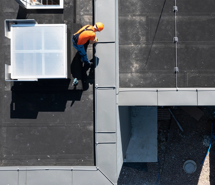 Professional commercial roofing installation featuring metal flashing, waterproofing components, and precision detailing on a flat roofing system.