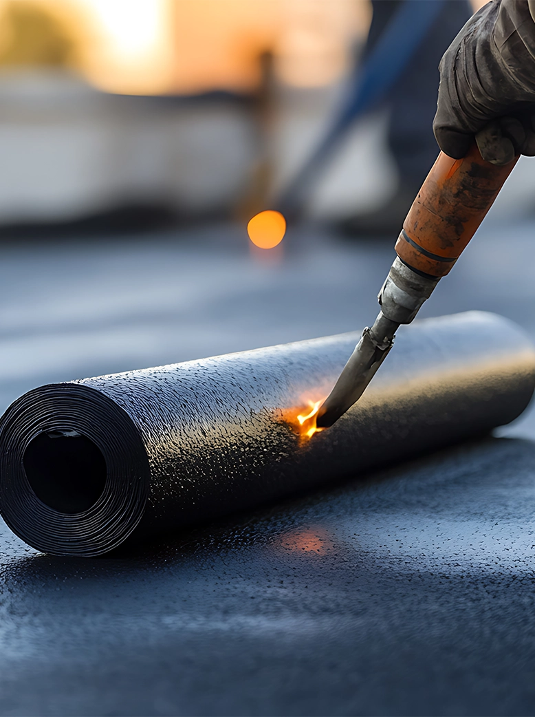Close-up of a roofing professional heat-welding modified bitumen membrane during a commercial flat roof installation.