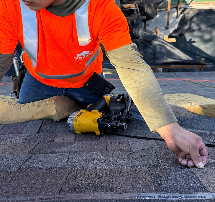 Close-up of a roofing contractor installing new shingles on a residential roof.