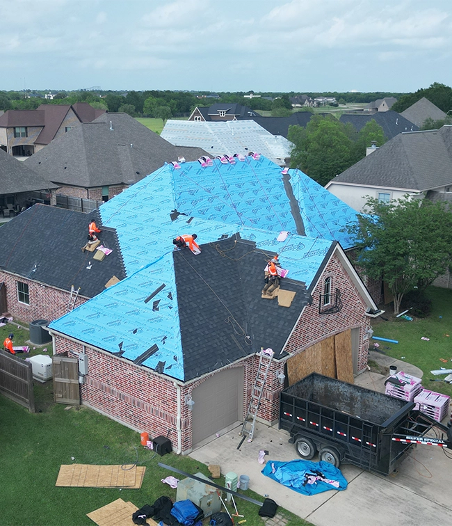 Roof replacement in progress on a residential home in Greater Houston with roofing crews installing new shingles and underlayment
